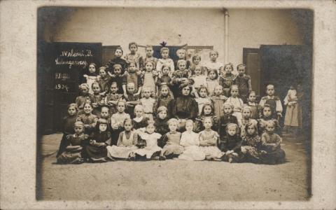 1907, azonos korú gyerekek, nem vegyes osztályok, hanem csupa kislány ül a tanító néni körül