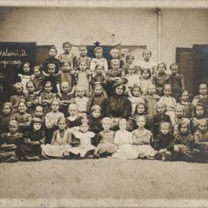 1907, azonos korú gyerekek, nem vegyes osztályok, hanem csupa kislány ül a tanító néni körül