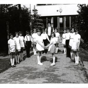 1971-ben készült a murakeresztúri iskola előtt. A modern külsejű iskola előtt népi ruhába öltözött gyerekek néptáncot tanulnak, háttérben áll a tanító nénijük.